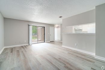 an empty living room and kitchen with a sliding glass door to a patio